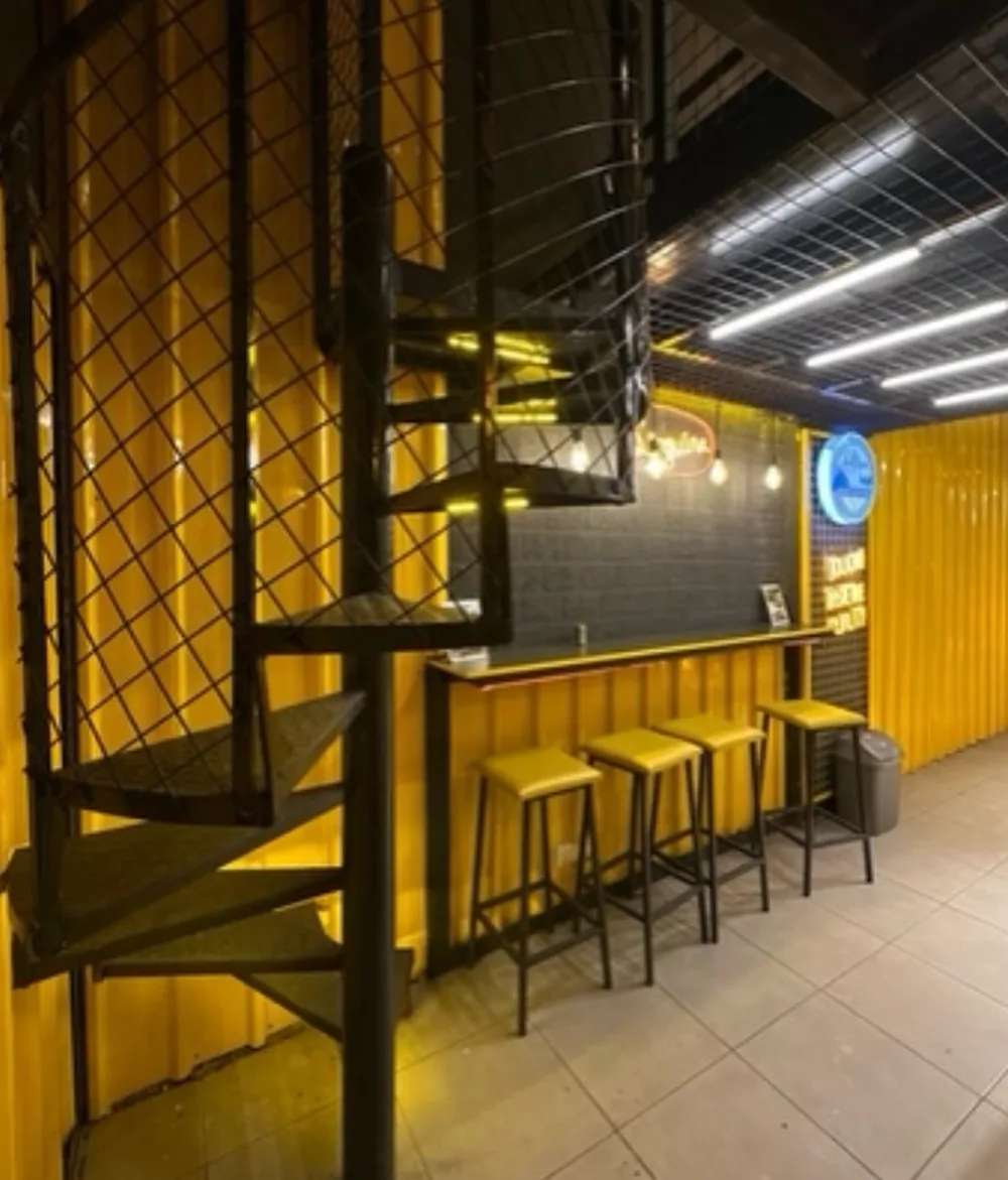 Spiral staircase beside the yellow container bar
